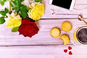 Hot coffee in a yellow mug, biscuit and mobile phone photo