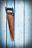 old rusty hand saw hanging on a blue wooden wall photo