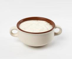 sour cream in a brown ceramic bowl on a white background, fermented milk product photo