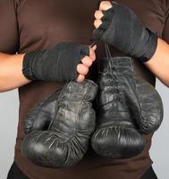 atleta con ropa marrón sostiene guantes de boxeo de cuero antiguos muy antiguos foto