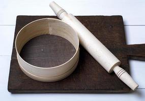 brown wooden kitchen cutting board, rolling pin and sieve photo