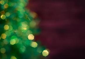 Blurred Christmas tree with garland, green bokeh on a dark red background blurred photo