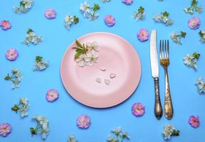 empty round pink ceramic plate and a vintage knife with a fork photo