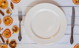 white empty dining plate with cutlery on a white wooden surface photo
