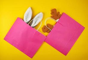 dos bolsas de papel rosas para ir de compras, dentro de la máscara navideña de un conejo y un ciervo foto