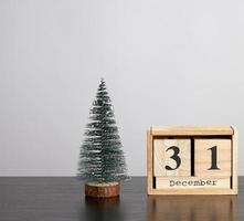 calendario de madera de cubos con la fecha del 31 de diciembre y árbol verde foto