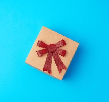 caja de regalo cuadrada con un lazo sobre un fondo azul foto