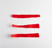 torn strips of red paper on white background photo