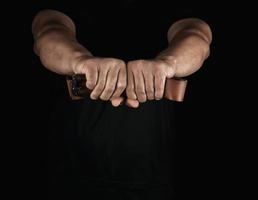 adult man in black clothes holding a brown leather belt with an iron buckle photo