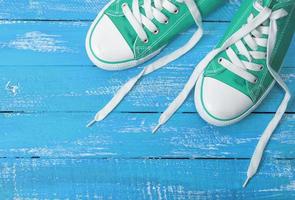 green textile sneakers on a blue wooden background photo