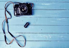 cámara de película antigua en una funda de cuero sobre una superficie de madera azul foto