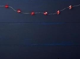 guirnalda navideña en llamas de pequeñas botas rojas sobre un fondo de madera azul foto