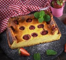 medio pastel de queso con fresas en un plato de grafito negro foto