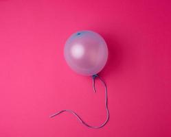 inflated blue rubber balloon on a pink background photo