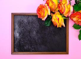 empty black frame and a bouquet of yellow roses photo