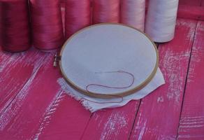 canvas in wooden hoop for embroidery on a pink background photo