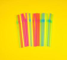 multicolored plastic cocktail tubes on a yellow background photo