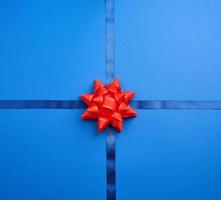 blue silk ribbon crossed on a dark blue background in the middle of a red bow photo