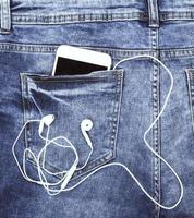 smartphone con auriculares en el bolsillo trasero de blue jeans foto