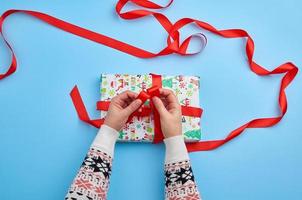 two female hands in a sweater knotted a red ribbon photo