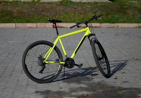 A yellow bicycle stands in the middle of the street on an autumn day photo