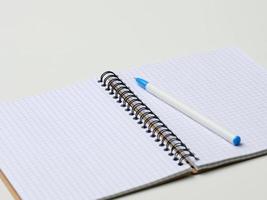 open blank notebook with pen on white table photo