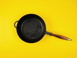 empty round black cast-iron frying pan with wooden handle photo