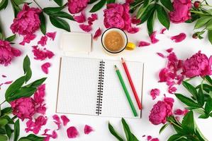 open notebook in a cage, wooden pencils and a yellow cup of coffee on a white background photo