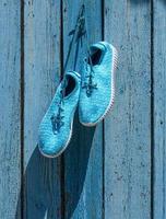 textile sneakers hang on a nail against the background of blue old boards photo