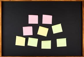 empty square multi-colored stickers hang on a black board in a wooden frame photo