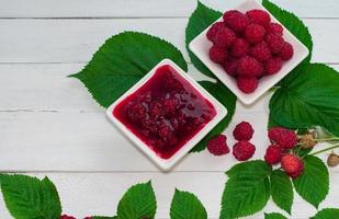 mermelada de frambuesa y frambuesas frescas maduras en el platillo foto