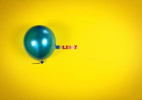 Blue balloon and inscription holiday on a yellow surface photo