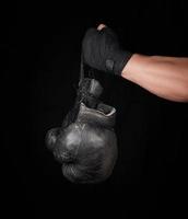 men's arm wrapped in a black elastic sports bandage holds pair old vintage leather boxing gloves photo