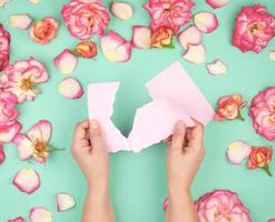 two hands hold an empty pink sheet torn from a notebook photo