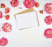 capullos de rosa rosa y un sobre de papel blanco sobre un fondo blanco foto