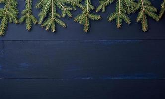 green branches of needles on a dark blue background from wooden boards photo