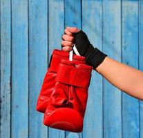 Red boxing gloves hanging on a rope in a woman's hand photo