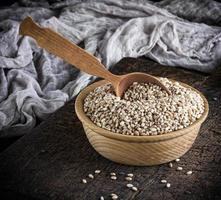 grano de trigo en un cuenco de madera sobre una mesa marrón foto