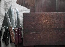 a lot of old different kitchen knives on a brown table photo