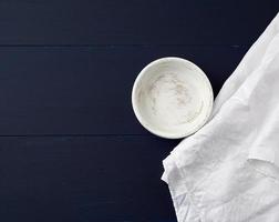 round wooden plate and white linen towel on blue wooden background photo