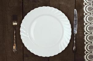 plato blanco con cubiertos sobre una superficie de madera foto