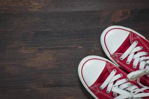 pair of red sneakers on a brown wooden surface photo