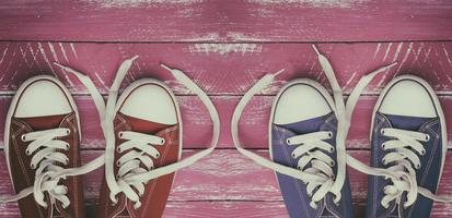 dos pares de zapatillas desgastadas sobre una superficie de madera vieja rosa foto
