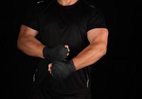 adult athlete in black uniform is standing in a rack with strained muscles photo