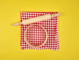 new wooden rolling pin on a red textile napkin and a round sieve for flour photo