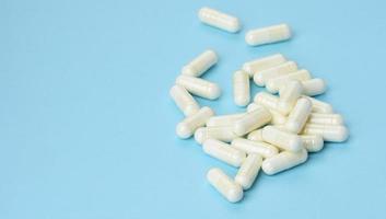 medical powder in white capsules on a blue background. Treatment pills, nutritional supplements photo