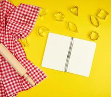 new wooden rolling pin on a red textile napkin and open notebook photo