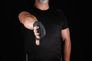 adult athlete in black uniform and hands rewound with textile bandage shows gesture dislike photo