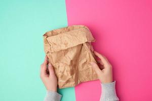 open brown paper bag for food packaging with greasy stains on a yellow background photo