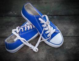 par de zapatillas azules jóvenes sobre una superficie de madera vieja foto